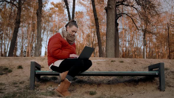 Young Woman works on a park bench