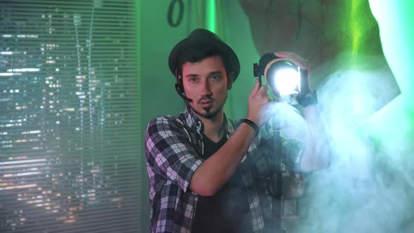 Filmmaker Looking at Camera While Using a Fresnel Lamp