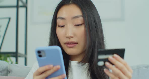 Close Up Smiling Asian Woman with Smartphone and Credit Card at Home