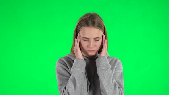 Portrait of Young Woman with Blond Hair Is Thinking About Something on a Green Screen