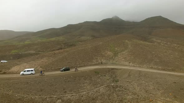 Aerial view of cyclists and cars driving through a curvy road in Fuerteventura.