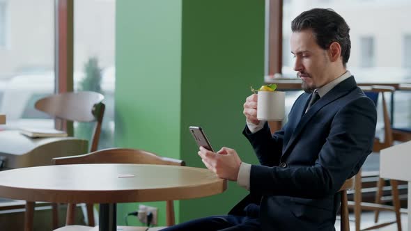 Side View of Concentrated Successful Businessman Drinking Healthful Tea and Surfing Internet on