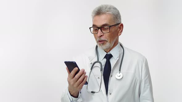 An Adult Doctor Is Holding a Phone and Reading Aloud Smiling