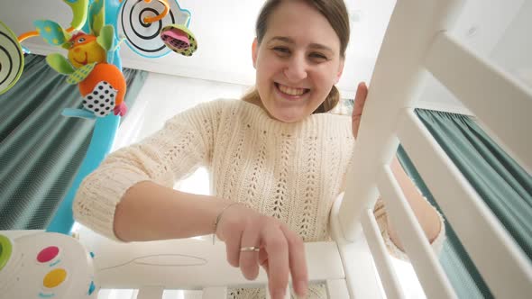 Portrait of Happy Smiling Woman Playing and Looking at Her Little Newborn Baby in Bed Concept of