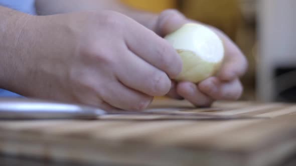 Static shot of a man peeling an onion