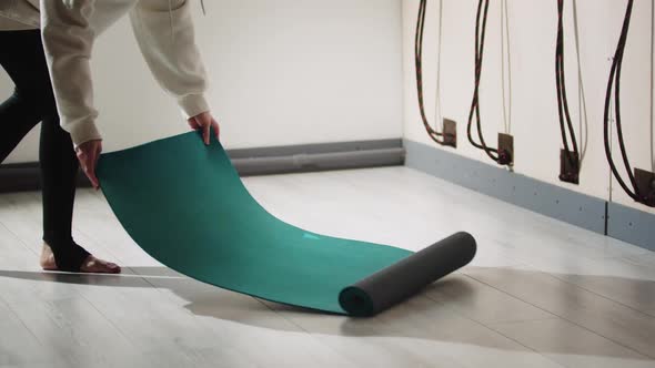 A Person Lays Out the Yoga Mat on the Floor
