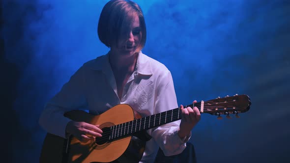 Girl Playing Guitar at Dark Studio