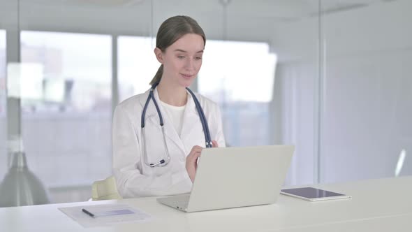 Cheerful Young Female Doctor Doing Video Chat on Laptop