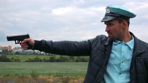 A Young Police Officer Shouts and Aims a Gun at Someone Off the Camera - View From the Side