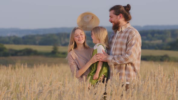 Happy Caucasian Family Stands in Wheat Field in Nature Outdoors Mother Holds Little Girl Daughter