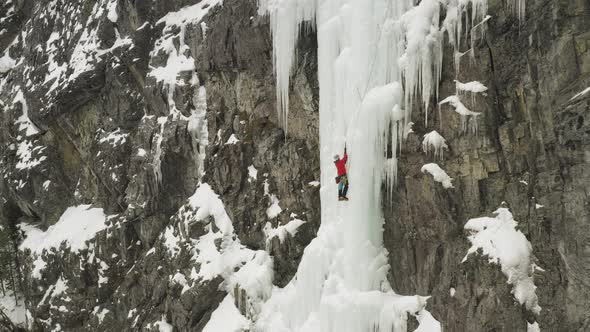 Spectacular aerial view ice climber scaling frozen cascade in Maineline, Kineo