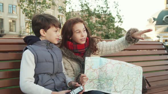 Young Guys Sit on a Bench and Take Pictures of Sights