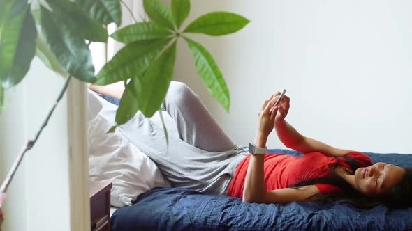 Woman using mobile phone in bedroom