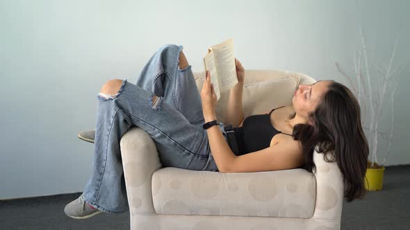 Young Woman Reading Book Fun on Armchair 4K