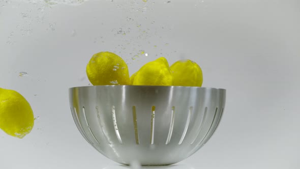 Lemons dropped in a fruit bowl in the water, Ultra Slow Motion alt