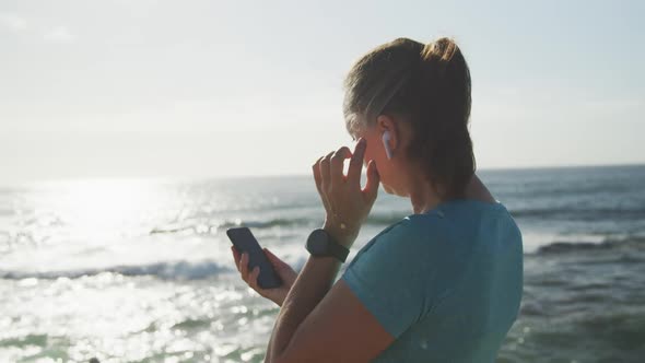 Senior woman using smartphone while running on a promenade