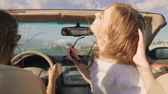 Portrait of two young beautiful and smiling hipster girls in convertible car