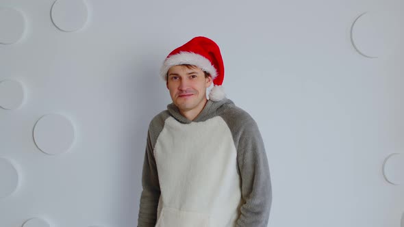 Happy Man in Santa Hat on Background of White Patterned Wall