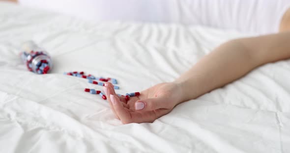 Hand with Medical Pills on Bed Closeup