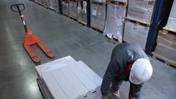 The Worker Packs a Pallet with Goods with Plastic Wrap