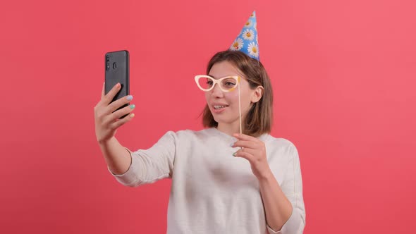 Close Up of a Woman in Party Hat Holding Birthday Accessories on Red Background.