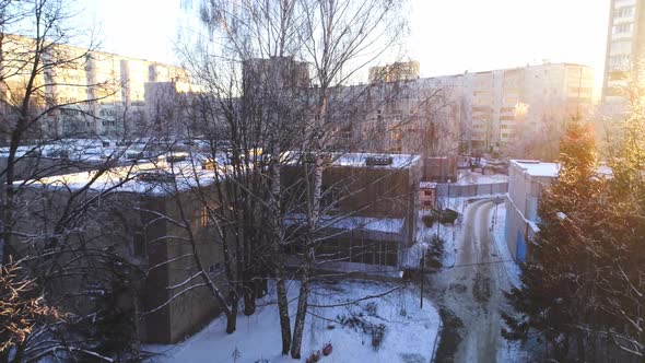 New School Building with Snowy Roof and Bare Trees in City