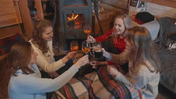 Happy Female Friends Making Toast While Sitting Near the Fireplace