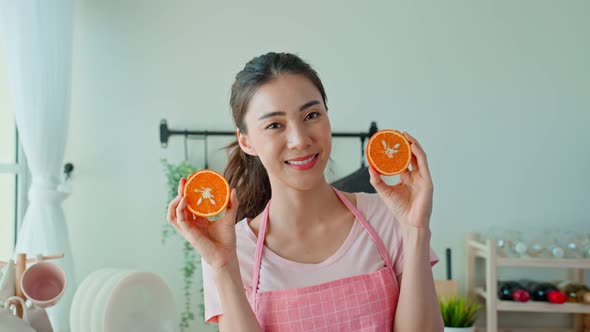 Portrait of Asian attractive woman enjoy healthy foods, holding orange and look at camera at home.