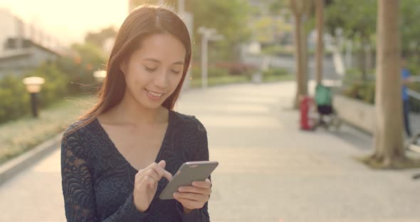 Woman use of mobile phone under sun flare