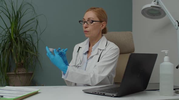 Female Doctor in Protective Gloves Filling Syringe with Vaccine Indoor