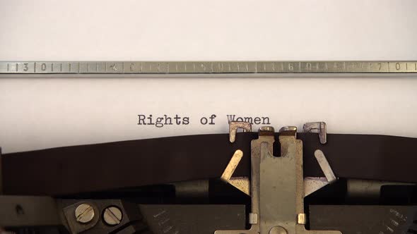 Typing phrase Rights of Women on retro typewriter. Close up.