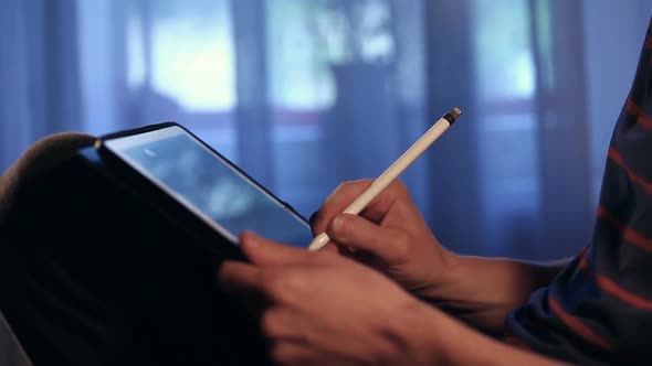 Artist Drawing a Picture Using His Tablet With Stylus at Home.