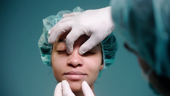 Surgeon Examines Girl's Face Before Rhinoplasty Wearing Protective Gloves