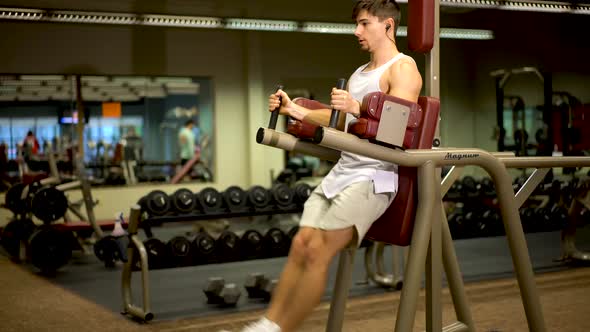 Front side shot of teen bodybuilder doing vertical leg lifts on a machine.