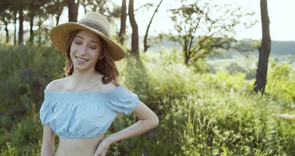 Cute Happy Girl Teenager in Straw Hat and Summer Clothes Looking to the Camera and Posing on Summer