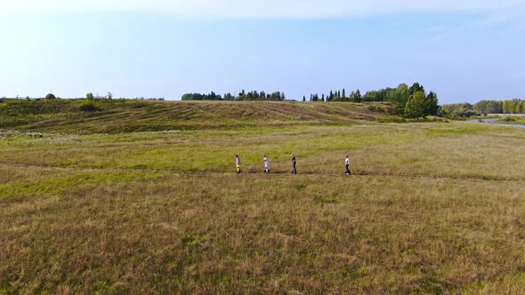 Four Teenagers Ride Across the Field Top View