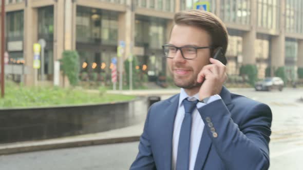 Businessman Talking on Smartphone while Walking in Street