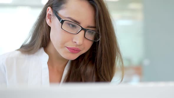 The Girl in the Workplace in the Office, Looking at the Monitor Screen.