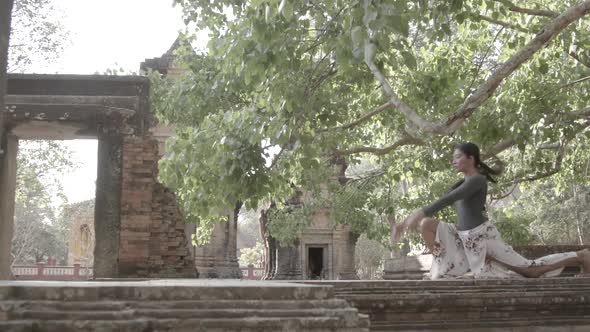 Beautiful, healthy young Asian women practices yoga at a SE Asia temple.