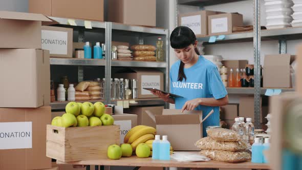 Female Volunteer Working at Food Bank with Digital Tablet