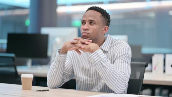 Young African Businessman Sitting in Office Thinking