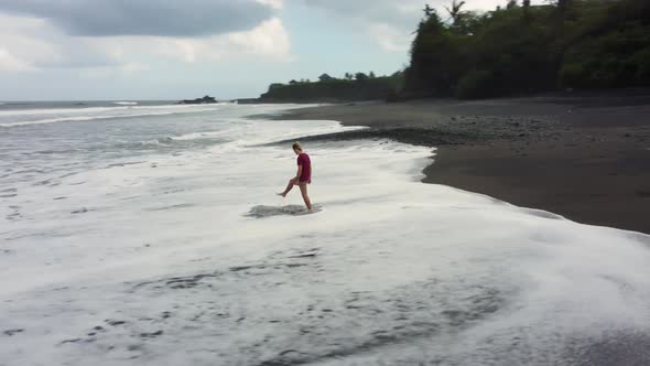 Man Walking on Black Sand Beach Before Storm