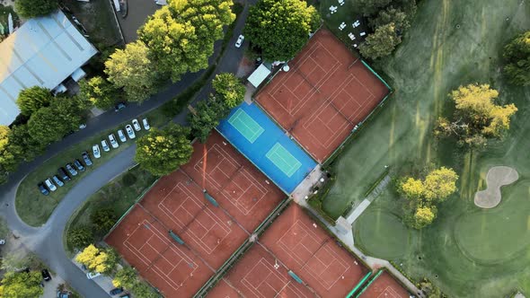 Aerial top down rising over a professional golf yard and clay tennis courts on a sport club at golde