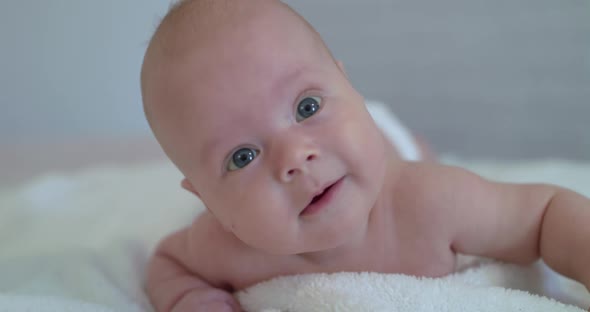 Portrait of Smiling Newborn Baby Lying and Moves on Bed