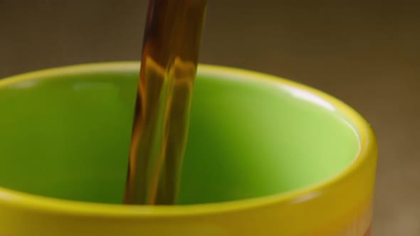 PAN LEFT, Black coffee is poured into a colourful mug, left steaming. 60fps