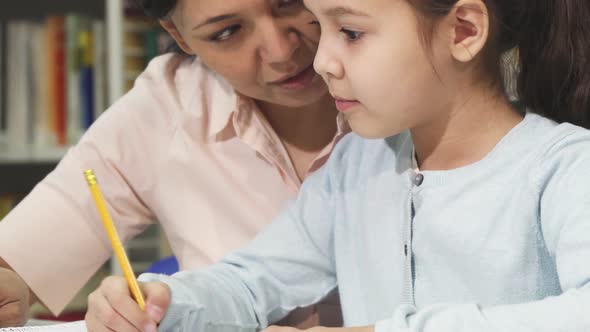 Close Up of a Cute Little Girl Studying with Her Mother