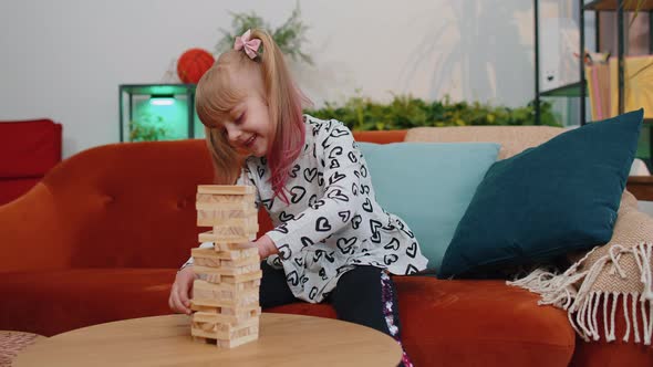 Funny Happy One Teenage Kid Girl Play Wooden Tower Blocks Bricks Game at Home in Modern Living Room