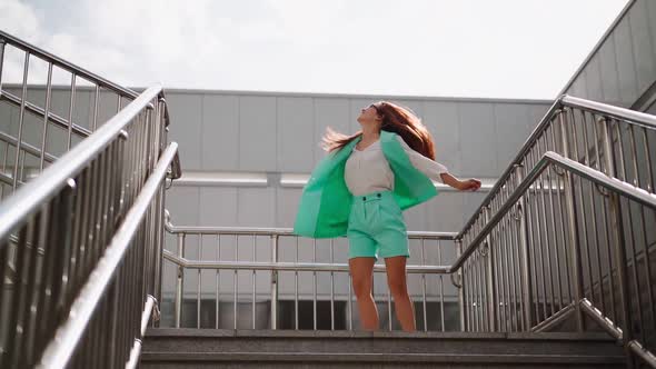 A beautiful slim woman in a trendy turquoise suit is spinning with happiness