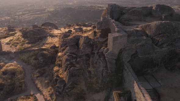 Aerial forward over defensive walls of Monsanto castle at sunrise. Portugal