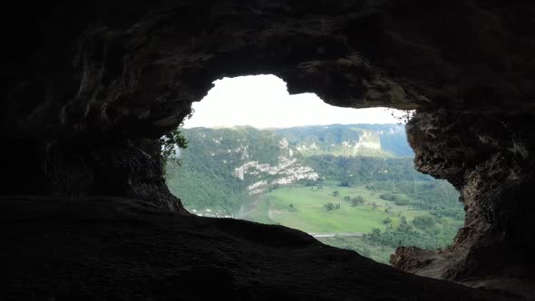 View from rocky cave on green forested valley and river